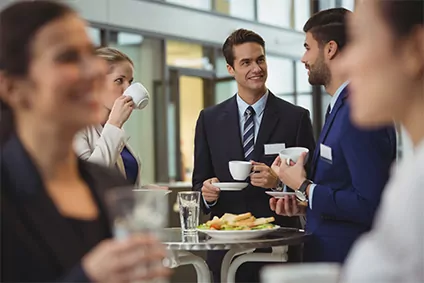 Geschäftsmänner und -frauen, die gemeinsam Kaffee aus einem leitungsgebundenen Kaffeevollautomaten trinken