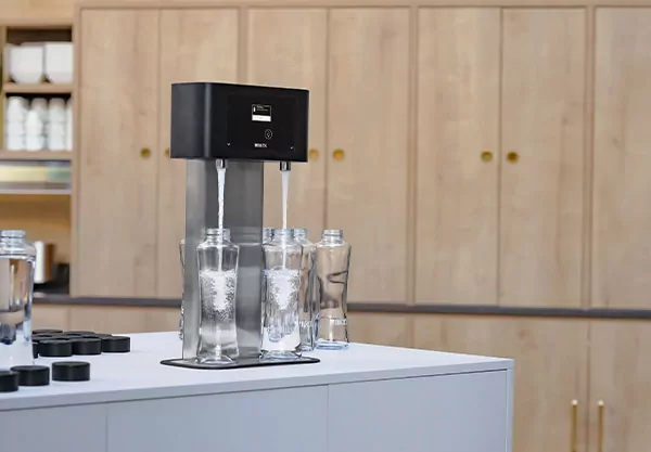 Wasserspender Brita T Tap, der auf einer Arbeitsplatte steht und zeitgleich zwei Glasflaschen mit Wasser befüllt.